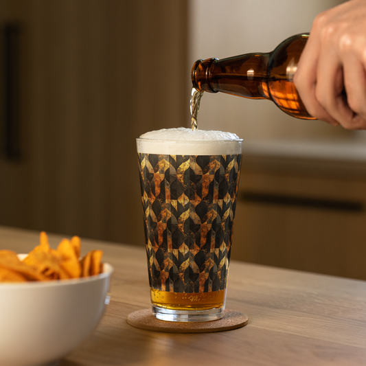 Aged Elegance charcoal and bronze pattern pint glass and a hand pouring beer into it with a bowl of chips on a wooden table.