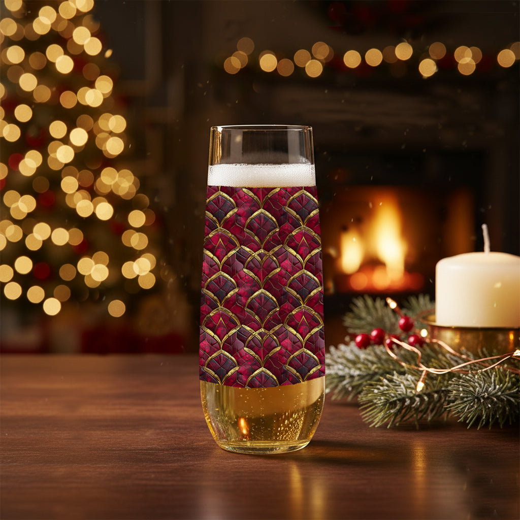 Crimson Jewels stemless champagne glass with a ruby and gold design on a table in front of a Christmas tree and fireplace.