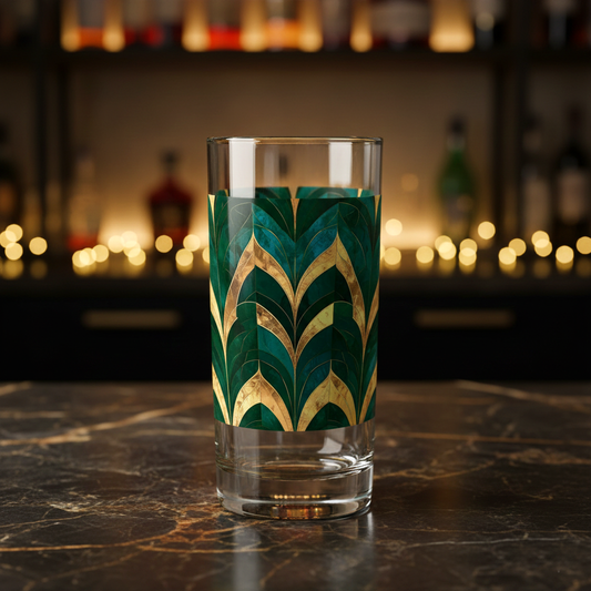 Emerald Royale decorative highball clear glass with green and gold pattern on a dark marble surface wth blurred background