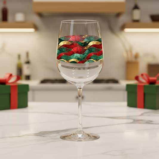 Royal Flux tall wine glass with green, red, and gold wavy design on a marble kitchen counter with green gift boxes and blurred background.