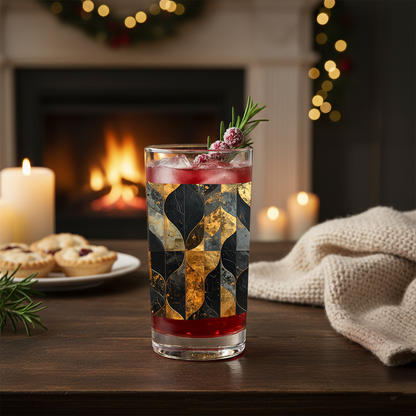 Aged Elegance highball glass of cocktail with charcoal and bronze decorative design on a table in front of a fireplace with candles and a throw.