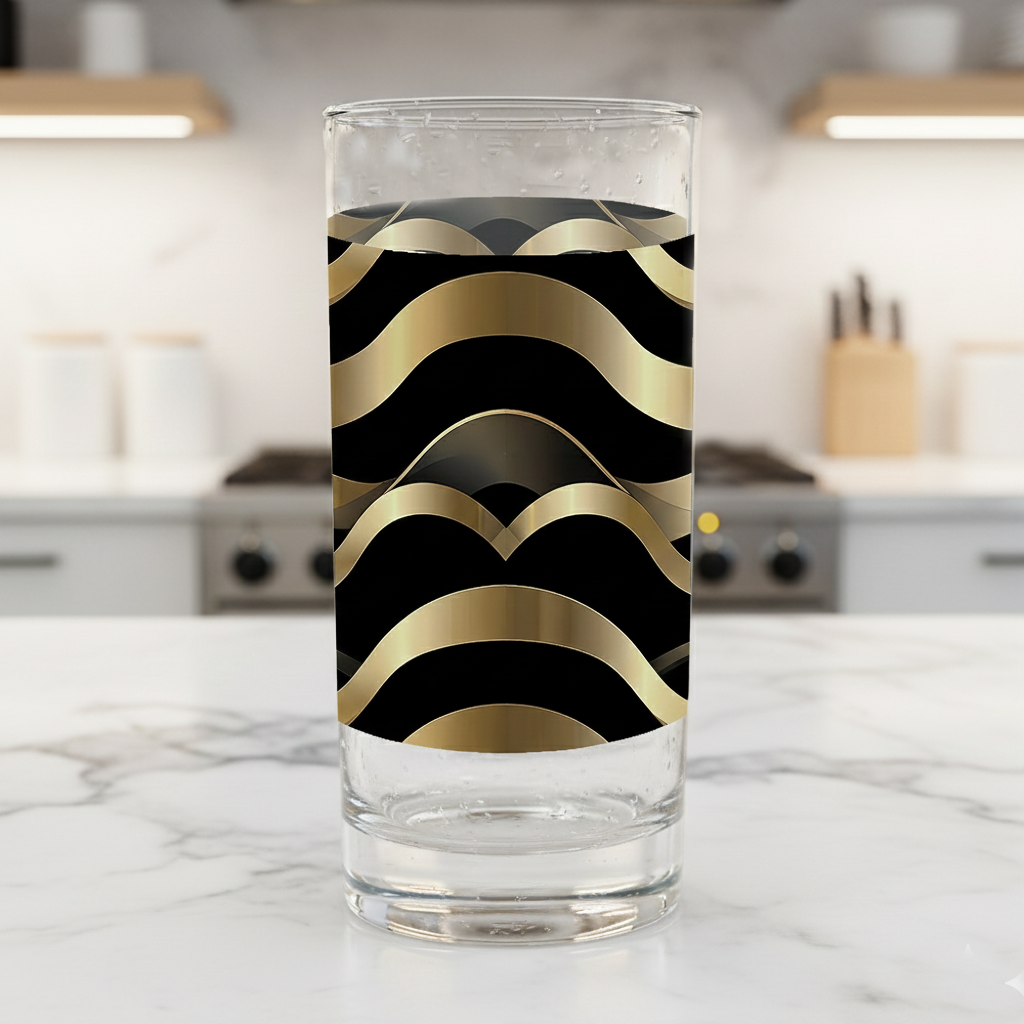 Liquid Gold highball glass with black and gold Art-Deco design closeup on a kitchen counter and a blurred background.