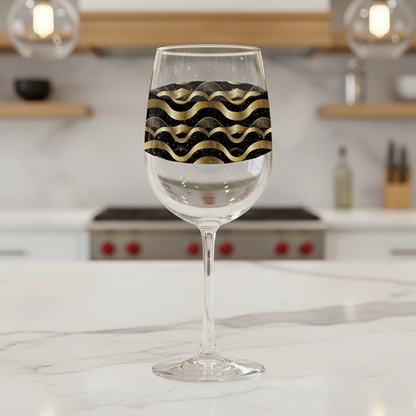 Liquid Gold tall wine glass with black and gold wavy design on a marble kitchen counter and blurred background.