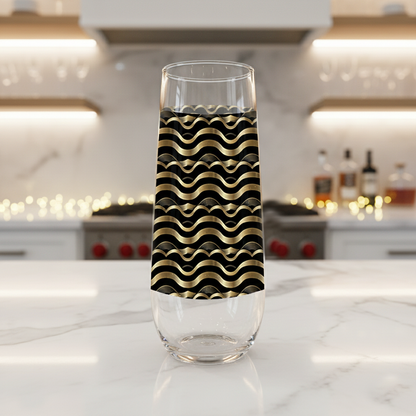 Liquid Gold stemless champagne glass with black and gold wavy Art-Deco design on a marble kitchen counter with blurred background.