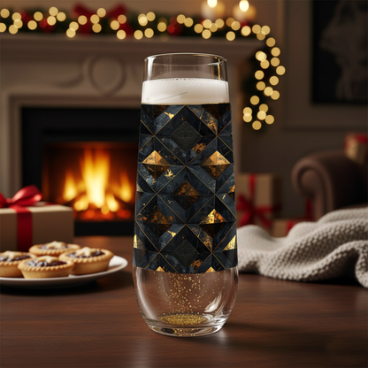 Gilded Decay stemless champagne glass with charcoal and gold geometric pattern on a table in front of a fireplace with Christmas decorations.