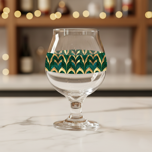 Emerald Royale Belgian clear glass with green and gold decorative design on a marble surface with blurred background