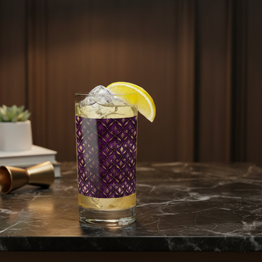Royal Opulence hightball glass with cocktail and lemon wedge in decorative plum and gold design on a dark marble surface and dark background