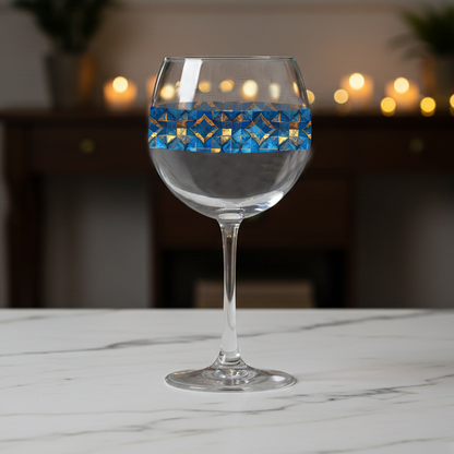 Moroccan Treasure balloon wine glass with turquoise and gold decorative design on a marble surface with blurred lights in the background