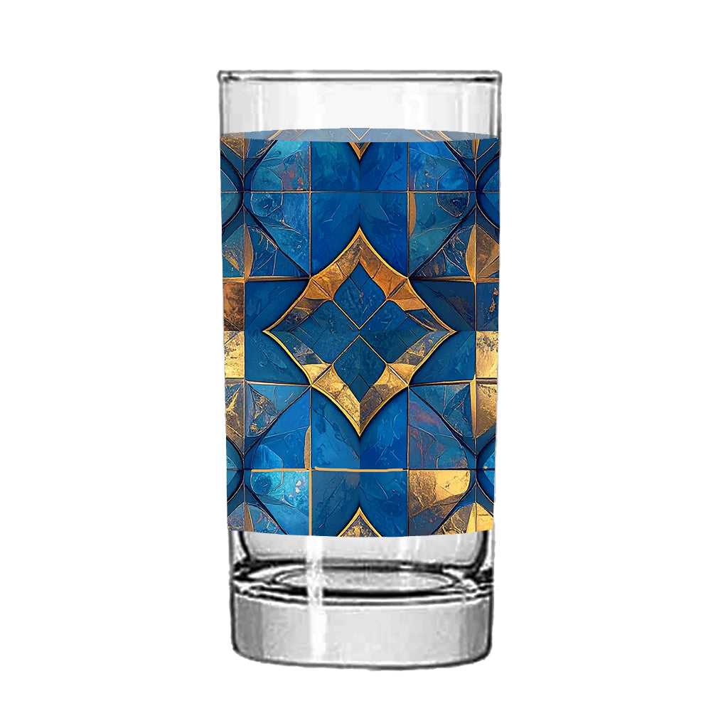 Clear highball glass with turqoise and gold geometric design on a white background