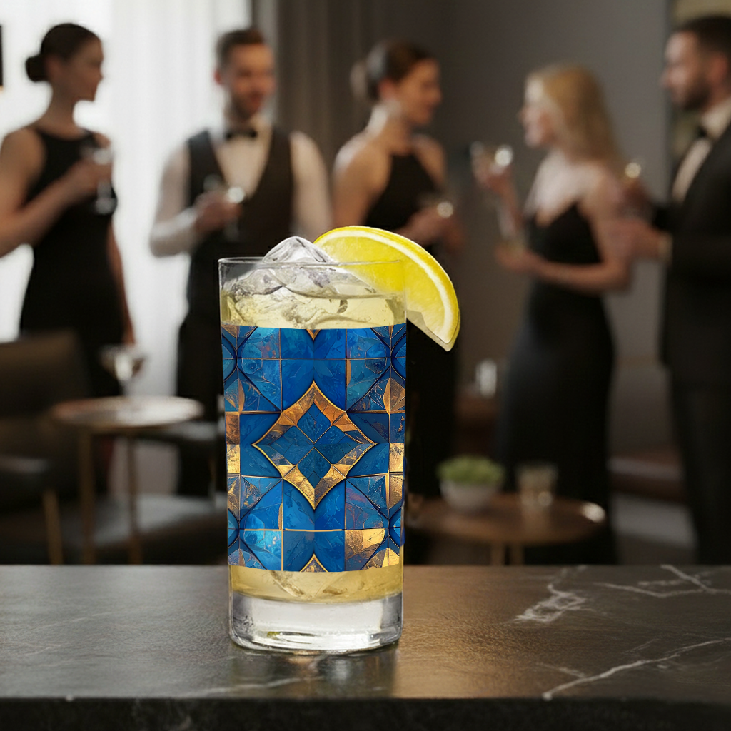 Moroccan Treasure highball glass with a turquoise and gold design, filled with a  cocktail sittihg on a bar, with people in formal attire in the background.