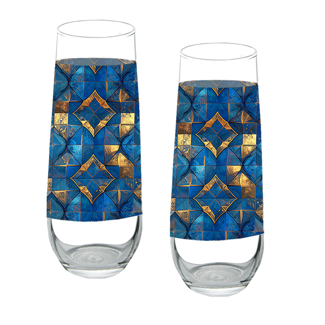 Two stemless champagne glasses with turqoise and gold geometric design on a white background