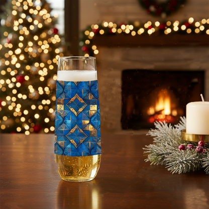 Moroccan Treasure stemless champagne glass with blue and gold geometric design on a table in front of a Christmas tree and fireplace.
