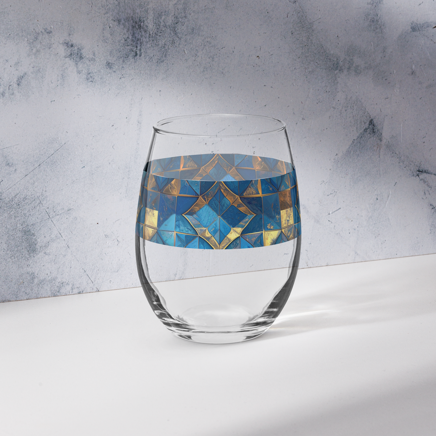 Moroccan Treasure stemless wine glass  with blue and gold geometric pattern on a gray surface