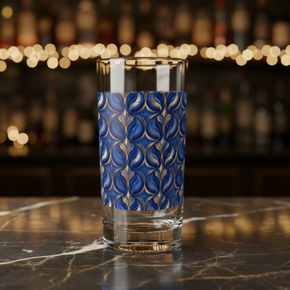 Sapphire Oracle highball glass  with blue and gold decorative pattern on a marble surface with blurred bar background