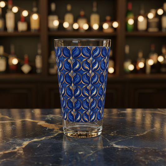 Sapphire Oracle pint beer glass with blue and gold pattern on a bar counter with blurred bottles in the background