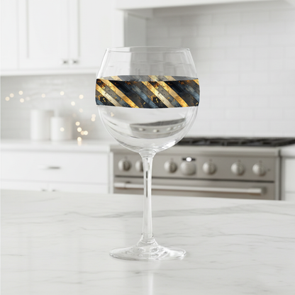 Obsidian Stripes balloon wine glass with gold and black diagonal stripes on a kitchen counter
