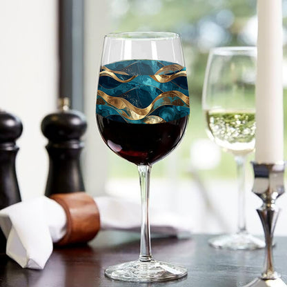 Opulent Teal tall wine glass with red wine highlighting flowing teal and gold wave design and sitting on  a table setting with kitchen objects.