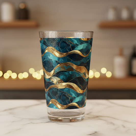 Opulent Teal pint beer glass with teal and gold wave design on a marble surface with blurred background.