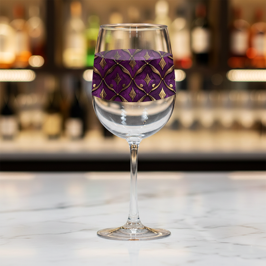 Royal Opulence wine glass with a decorative plum and gold design on a marble bar counter with blurred background