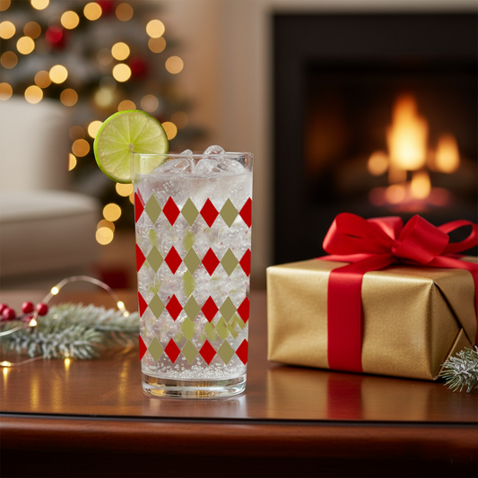 Ruby and Gold  highball glass in a harlequin design, and a cocktail drink and lme wedge on a table next to a wrapped gift in a festive setting.