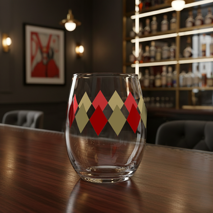 Ruby and Gold stemless wine glass with a diamond pattern on a wooden table in front of a bookcase and painting.